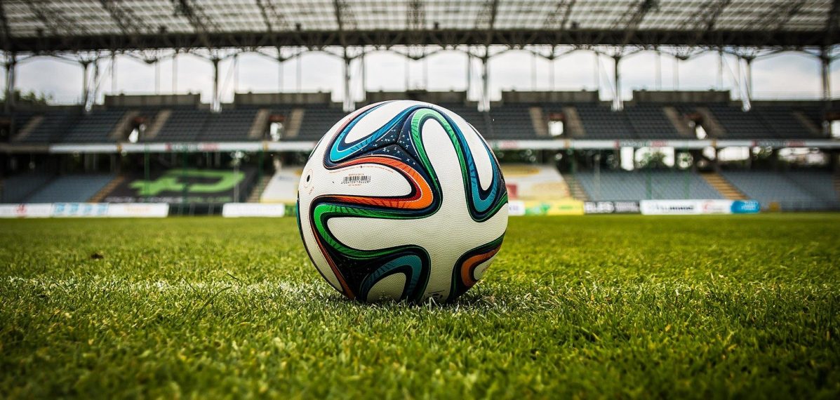 Ein Fußball liegt auf dem Rasen in einem leeren Stadion.
