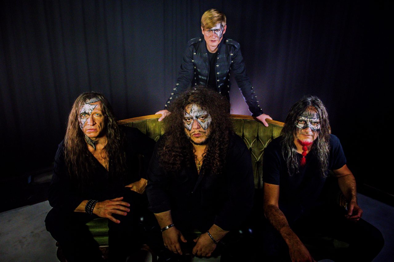 Die vier Mitglieder von Iron Mask posieren für die Kamera mit silberner Schminke um die Augen rum.