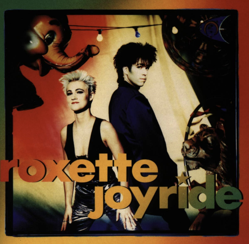 Auf dem Albumcover "Joyride" von Roxette sind Marie Fredriksson und Per Gessle zu sehen. Der Hintergrund ist sehr bunt und es sind eine Lichterkette, ein Elefant und ein Tiger zu sehen.
