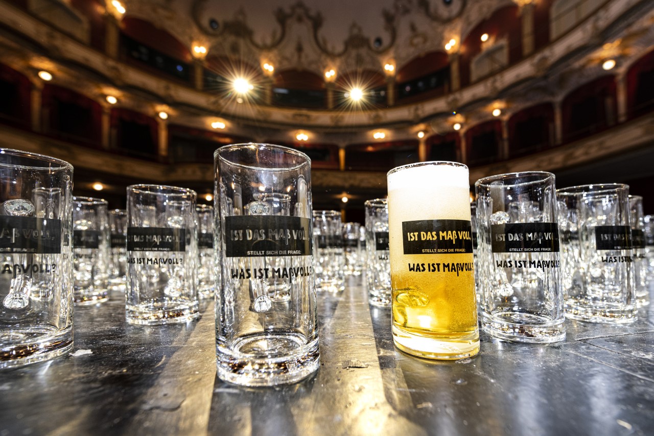 Auf dem Foto sieht man ein volles und zahlreiche Bierkrüge, die auf der Bühne des Fürther Stadttheaters stehen.