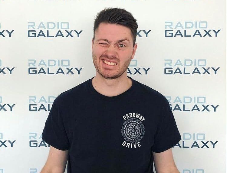 Felix Körting steht vor einer Werbewand, auf der "Radio Galaxy" steht.