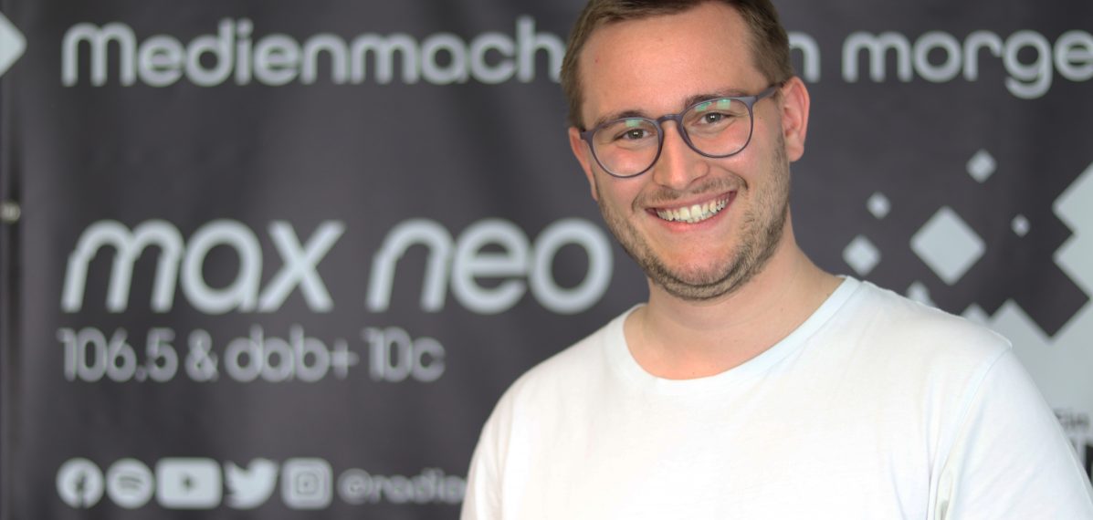 Sven Stefani steht vor einem max neo Banner.