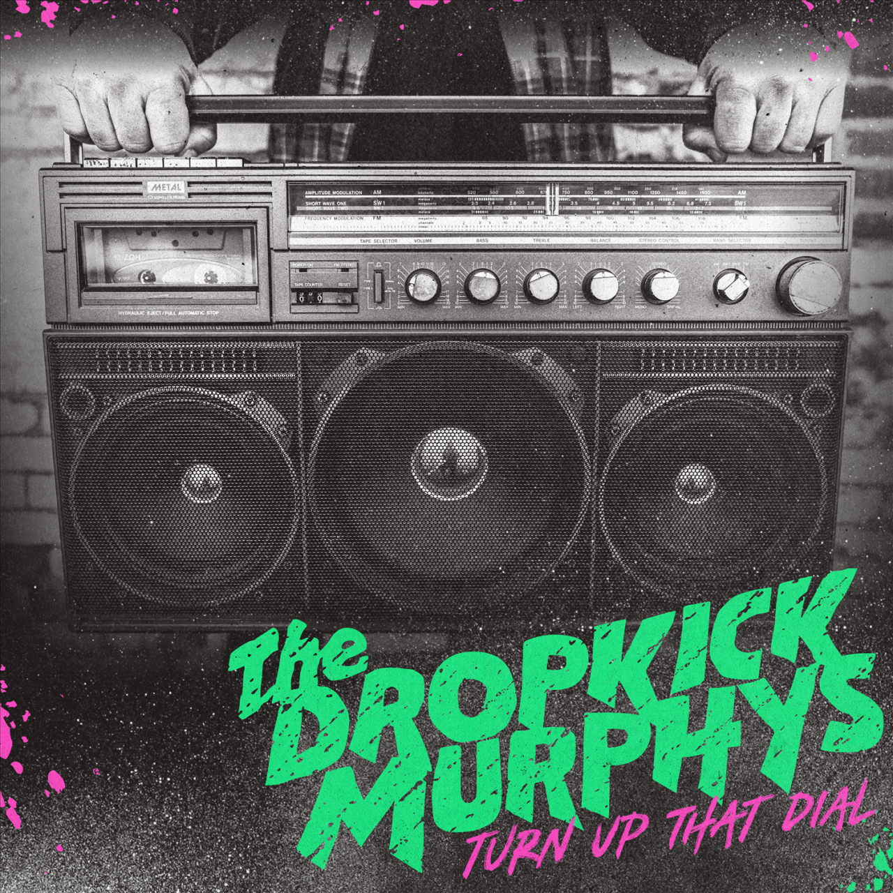 Das albumcover "Turn Up That Dial" von The Dropkick Murphys ist schwarz-weiß. Es zeigt einen großen Ghettoblaster. Der Bandname und der Albumtitel sind grün und pink.