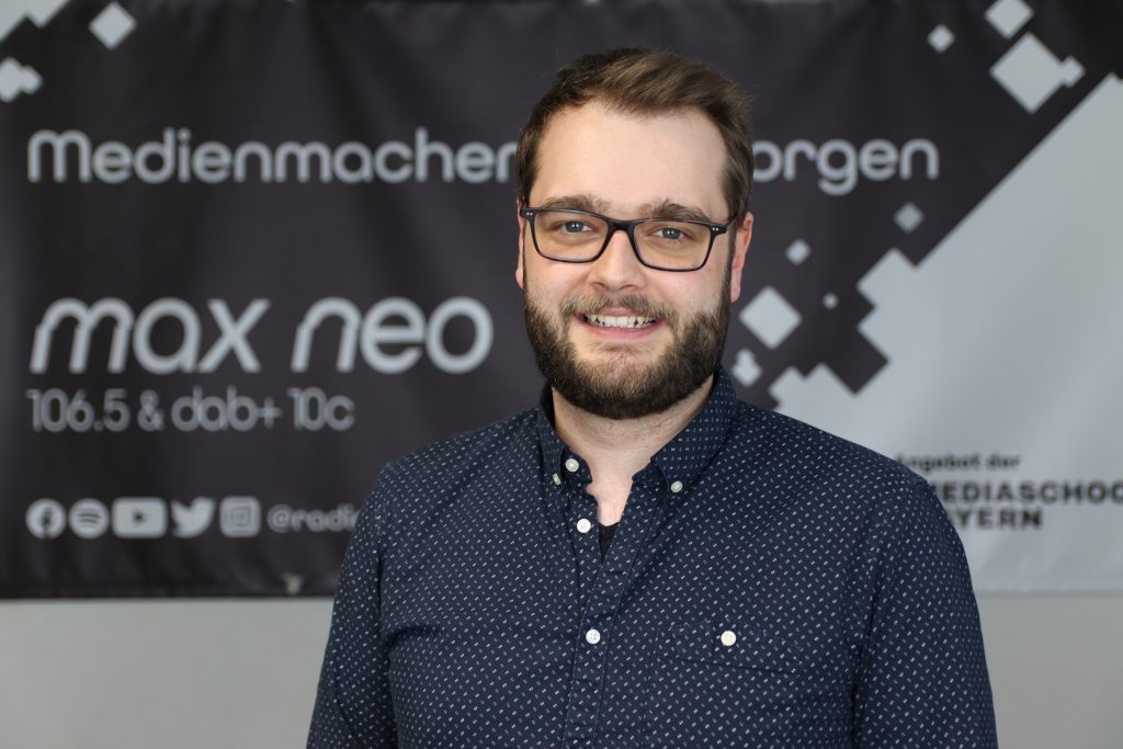 Maxi Auer steht vor dem max neo Banner.