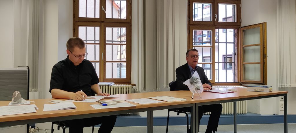Auf dem Foto sieht man zwei Herren aus dem Nürnberger Wahlamt, die an einem Tisch sitzen.