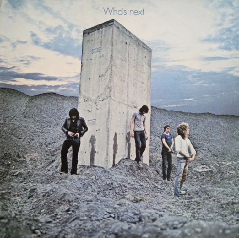 Das Albumcover "Who's Next" von The Who zeigt die Band, die in einer felsigen Landschaft vor einem Betonklotz steht.