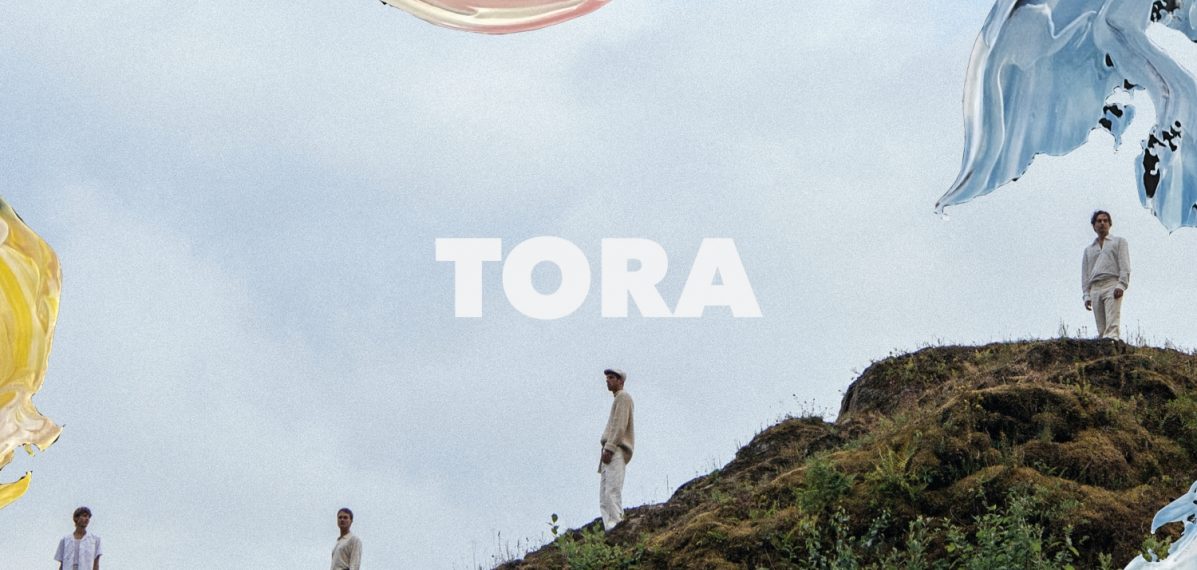 Das Albumcover "A Force Majeure" von Tora zeigt die Bandmitglieder, wie sie auf einem grasbewachsenen Hügel stehen. In den Ecken des Bildes sind verschiedene Pinselstriche mit Farbe zu sehen.