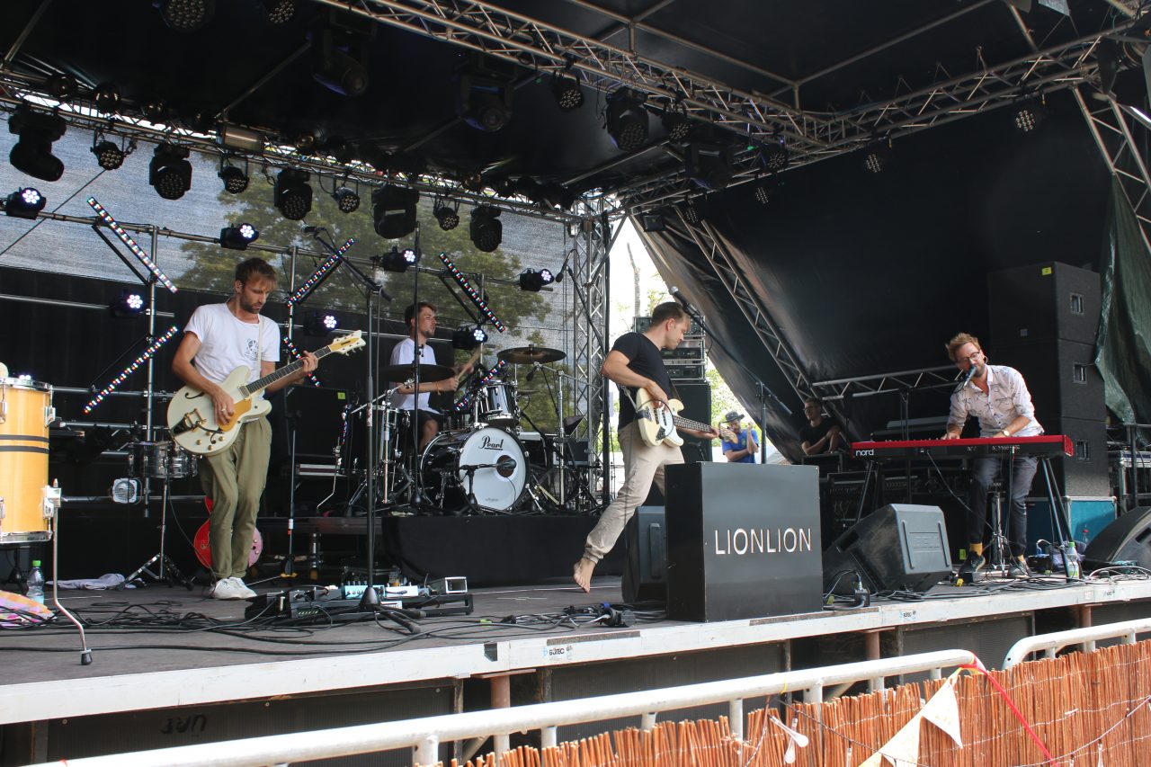 Das Foto zeigt LionLion bei ihrem Auftritt 2018 auf dem Weinturm Open Air in Bad Windsheim. Die vier Jungs spielen gerade einen Song auf der Bühne.