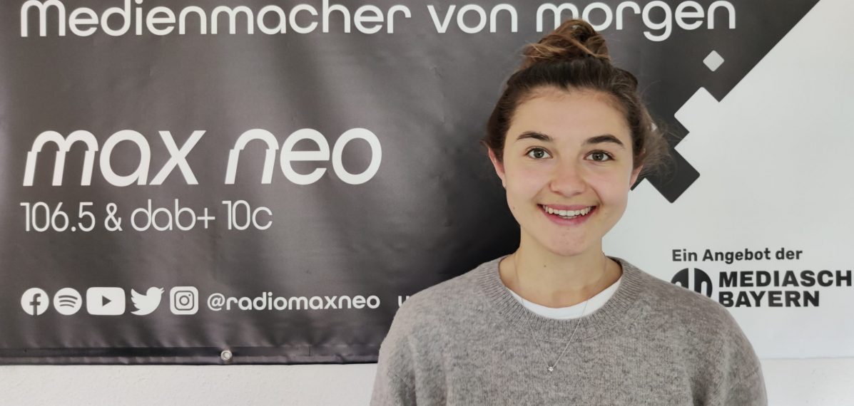 Paulina Behrendt steht vor dem max neo Banner. Sie ist im Porträt zu sehen.