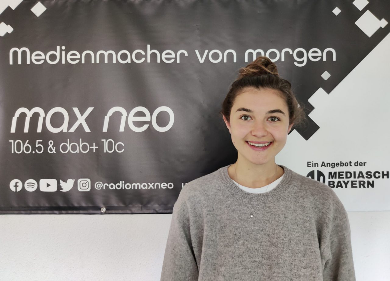 Paulina Behrendt steht vor dem max neo Banner. Sie ist im Porträt zu sehen.