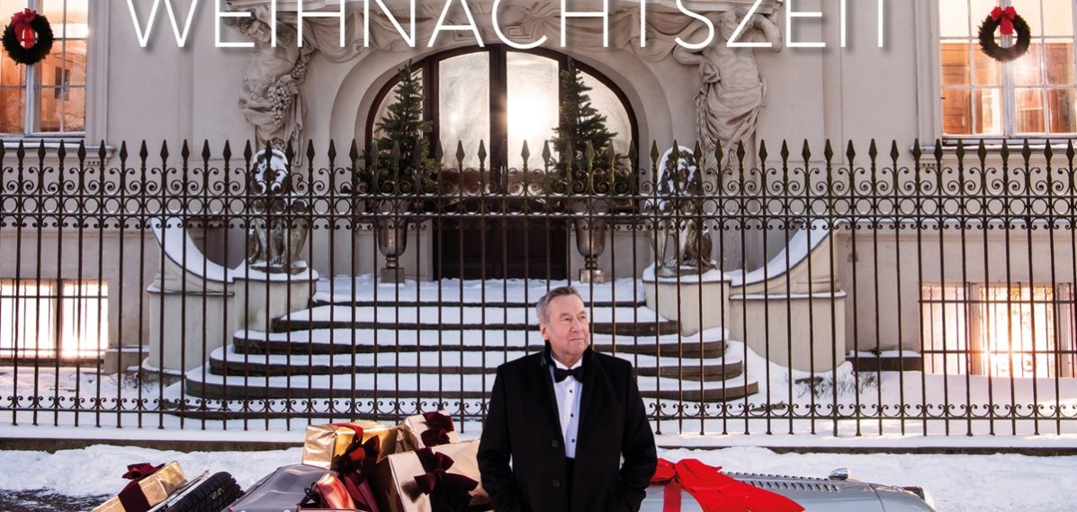 Das Albumcover "Weihnachtszeit" von Roland Kaiser zeigt den Musiker vor einem geschmückten und mit Geschenken beladenen Oldtimer, der vor einer ebenfalls geschmückten, herrschaftlichen Villa parkt.