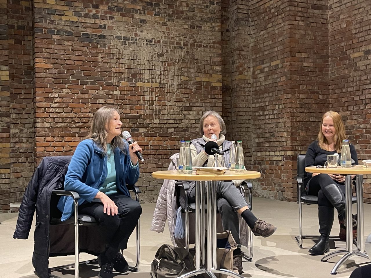 Monika Riedel, Olga Nikol und Dr. Astrid Betz sitzen an zwei Tischen und sprechen über das Valka-Lager.