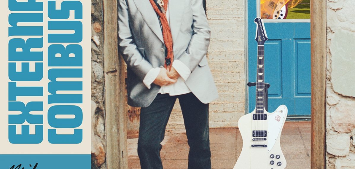 Das Albumcover "External Combustion" von Mike Campbell & The Dirty Knobs zeigt Mike Campbell, wie er in einem Türrahmen lehnt. Hinter ihm steht eine Gitarre.