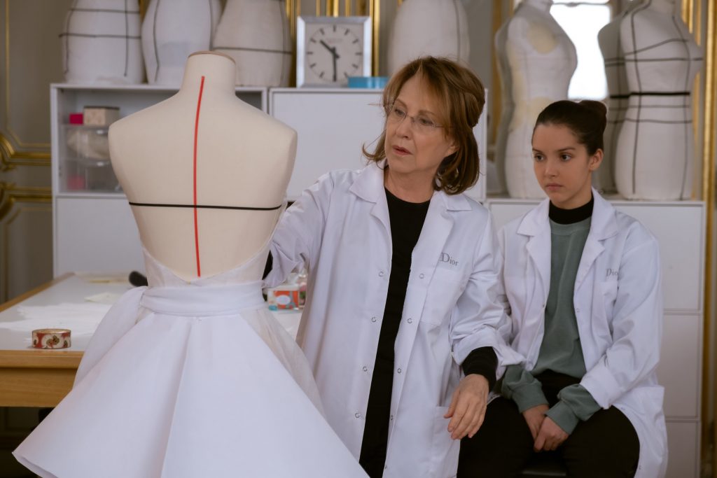 Das Foto zeigt eine Szene aus "Haute Couture". Esther schneidert an einem Kleid, während Jade über die Schulter guckt.