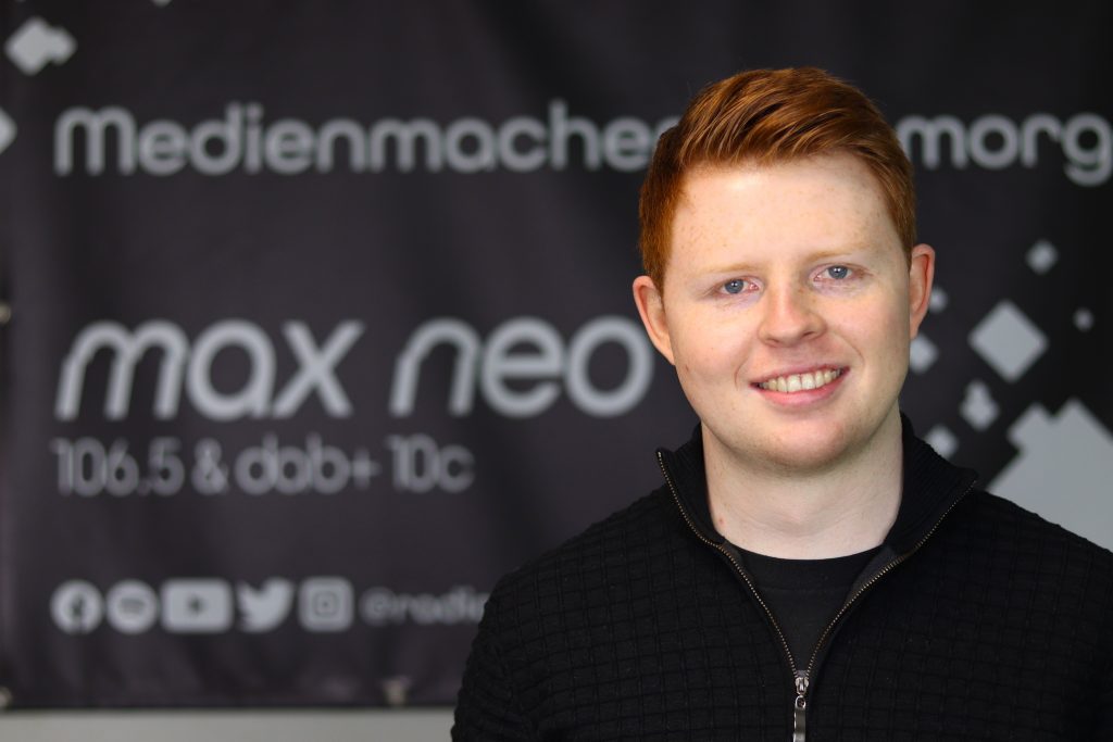 Das Foto zeigt Johannes George im Porträt vor dem max neo Banner.