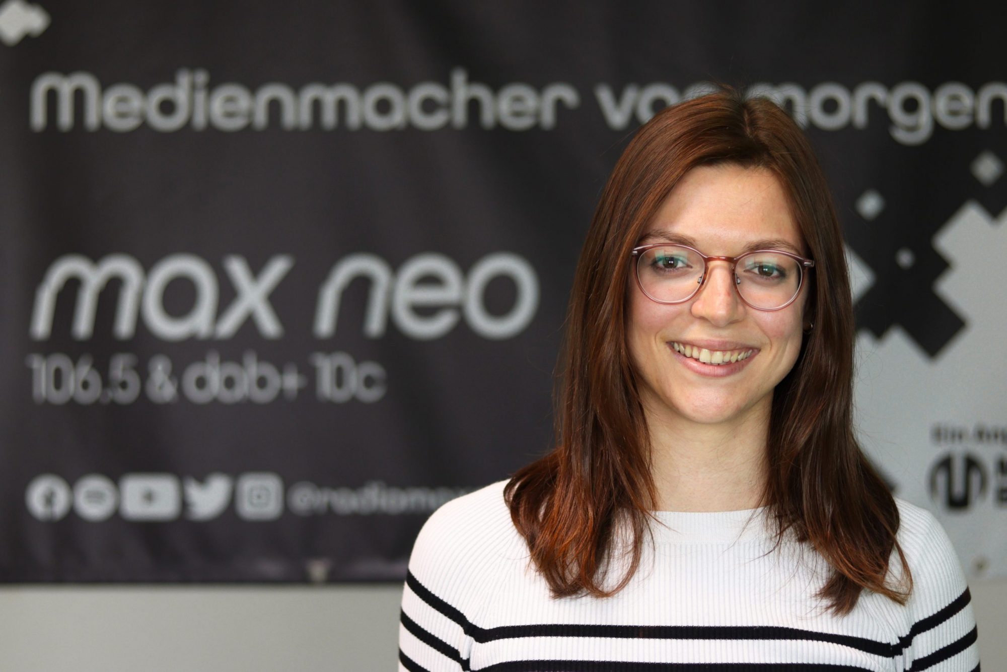 Auf dem Foto ist Laura Feuerlein im Porträt vor dem max neo Banner zu sehen.