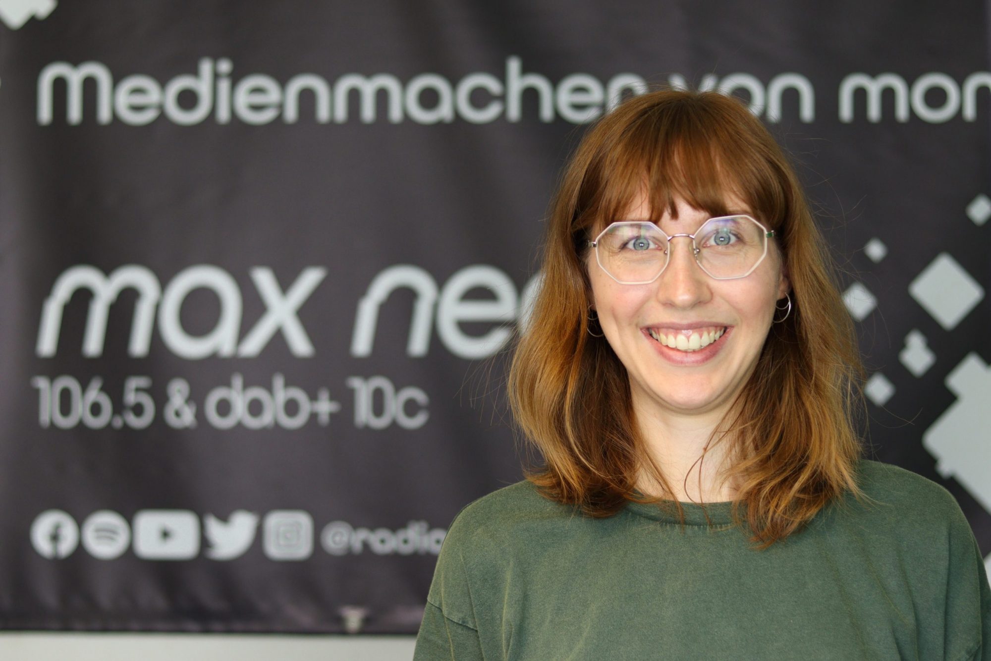 Maria Czerniejewski ist im Porträt vor dem max neo Banner zu sehen.