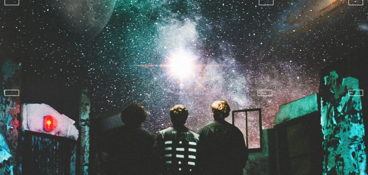 Album-Cover: Die drei Bandmitglieder von The Kooks stehen in einem offenen Raum mit Blick auf eine entfernte Galaxie im Weltraum.