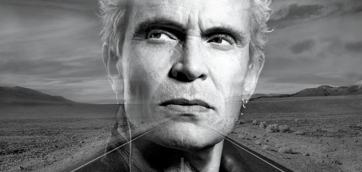 Das Albumcover "The Roadside" von Billy Idol zeigt den Musiker im Porträt in schwarz-weiß. Sein Kopf ist transparent. Hinter seinem Kopf ist eine Wüstenlandschaft ebenfalls in schwarz-weiß zu sehen.