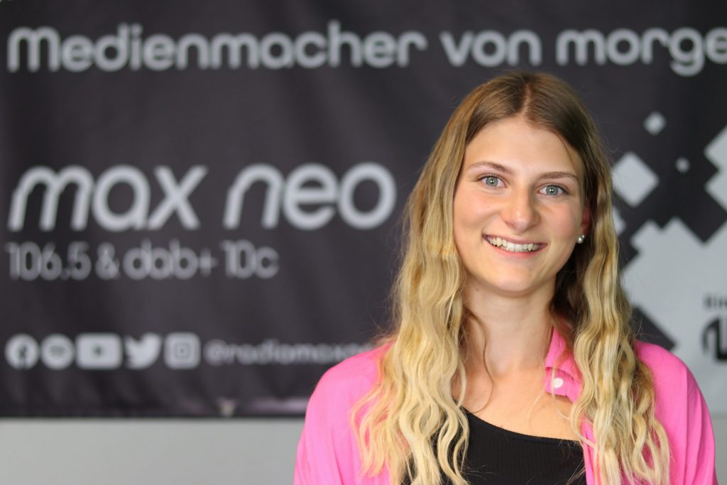 Auf dem Foto ist Julia Schmidt zu sehen, die im Porträt vor dem max neo Banner zu sehen ist.