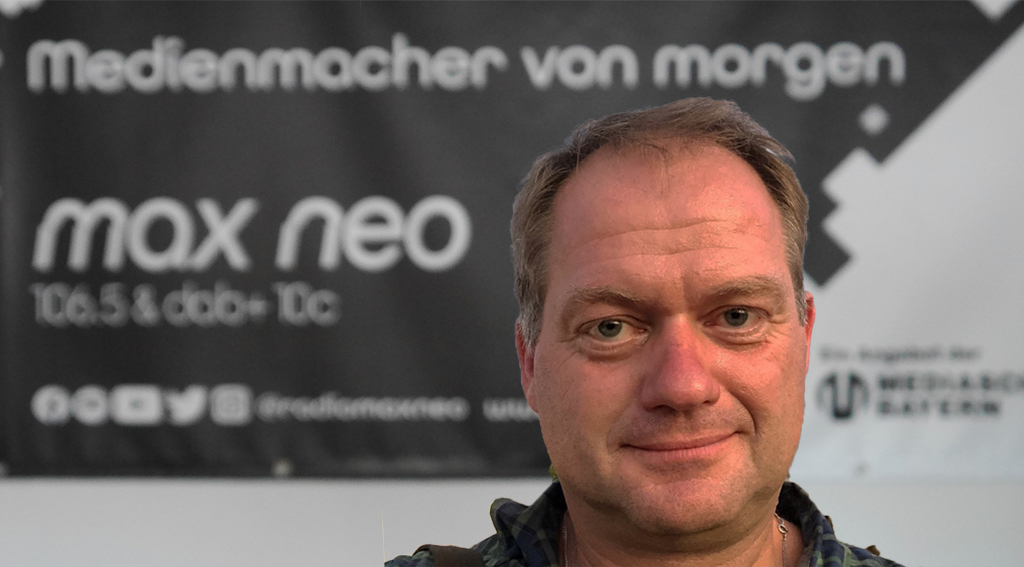 Arndt Peltner steht vor dem max neo Banner und ist im Porträt zu sehen.