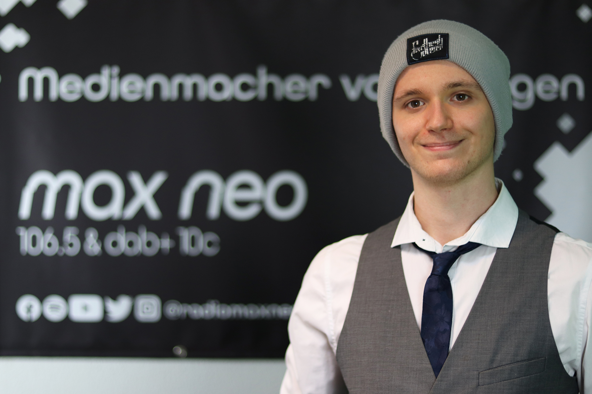 Philipp Lorenz steht vor dem max neo Banner und ist im Porträt zu sehen.