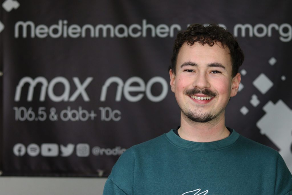 Das Foto zeigt Moritz Steidl im Porträt vor dem max neo Banner.