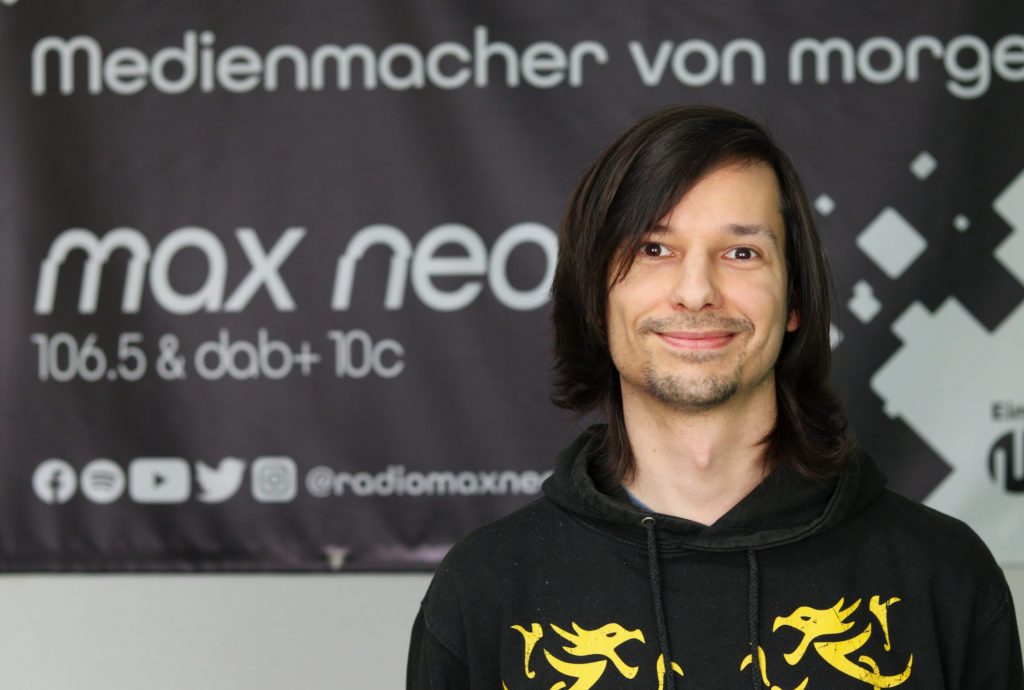 Das Foto zeigt Rainer Sigl im Porträt vor dem max neo Banner.