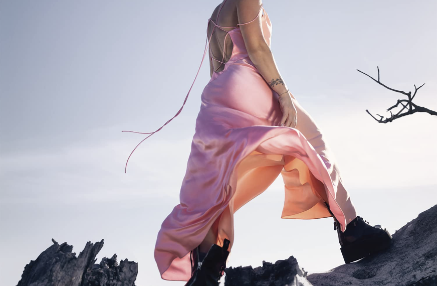 Das Albumcover "Trustfall" von Pink zeigt die Sängerin in einem rosafarbenen Kleid, wie sie auf Felsen steht.