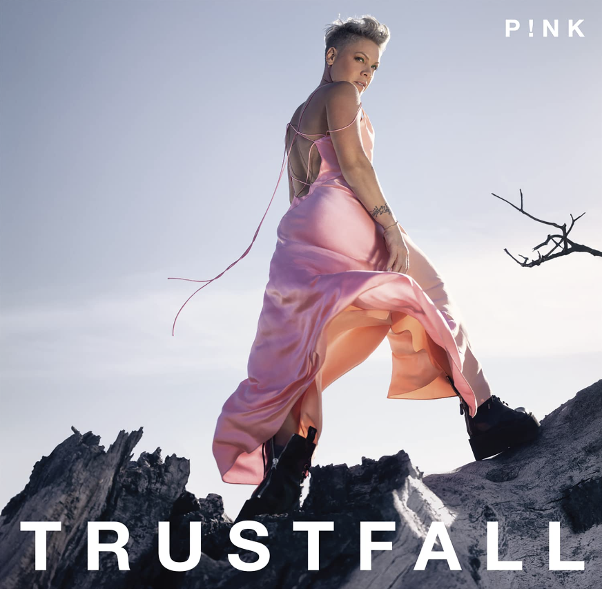 Das Albumcover "Trustfall" von Pink zeigt die Sängerin in einem rosafarbenen Kleid, wie sie auf Felsen steht.