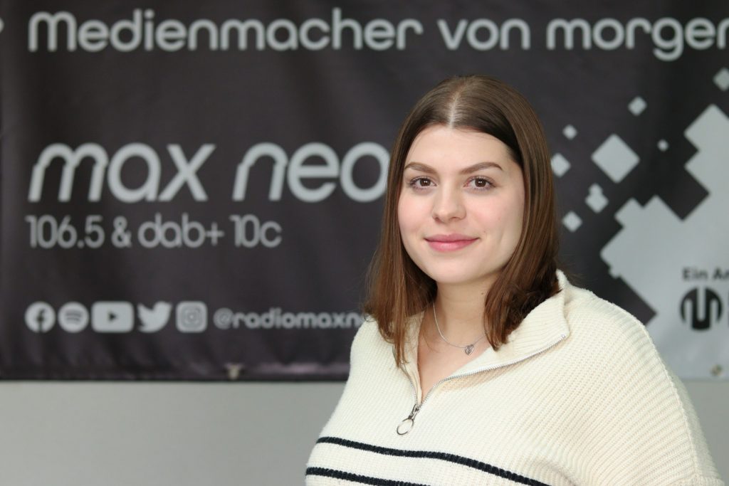Das Foto zeigt Sarah Kürzdörfer im Porträt vor dem max neo Banner.