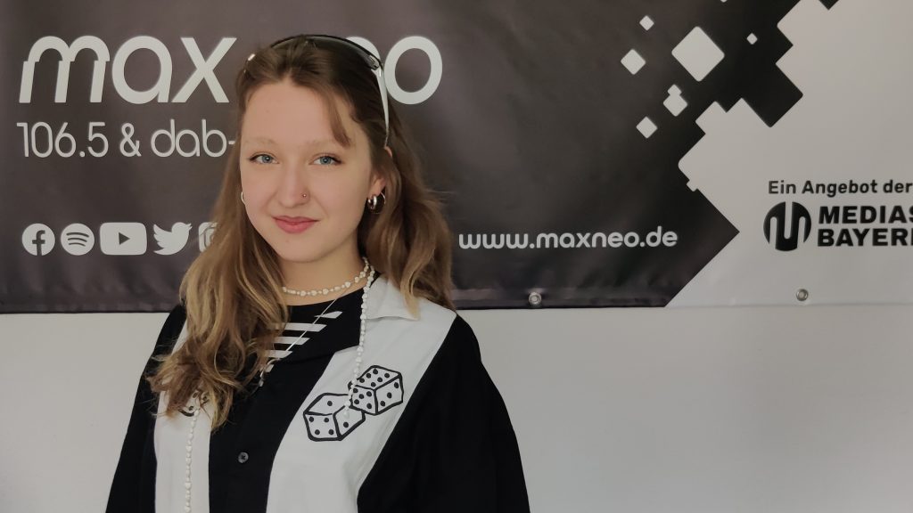 Das Foto zeigt Cathy Cyfka, die vor dem max neo Banner steht.