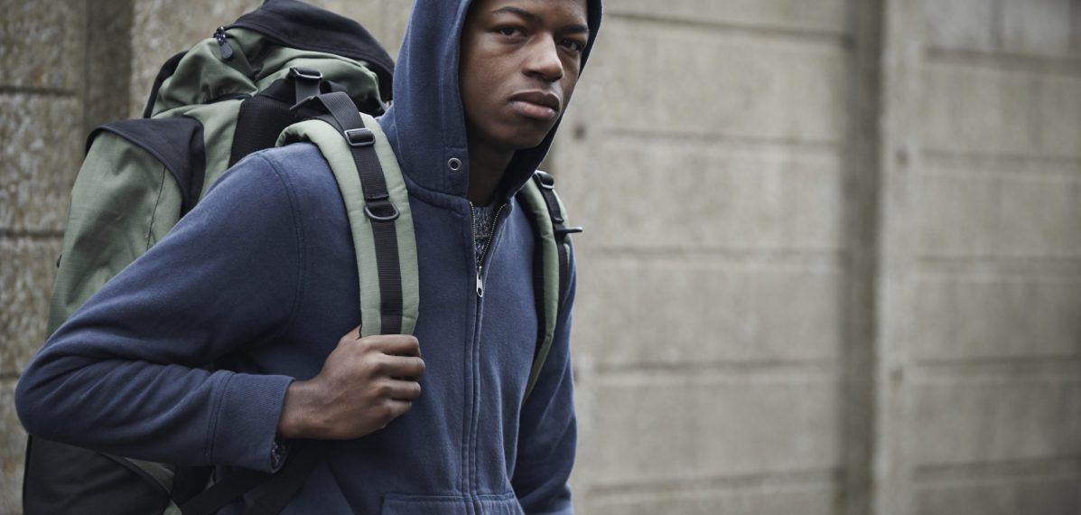 Das Foto zeigt einen schwarzen Jugendlichen mit Kapuze und Rucksack.