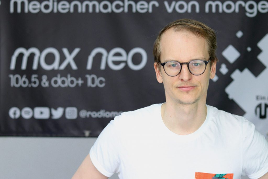 Das Foto zeigt Dominik Fechner im Porträt vor dem max neo Banner.