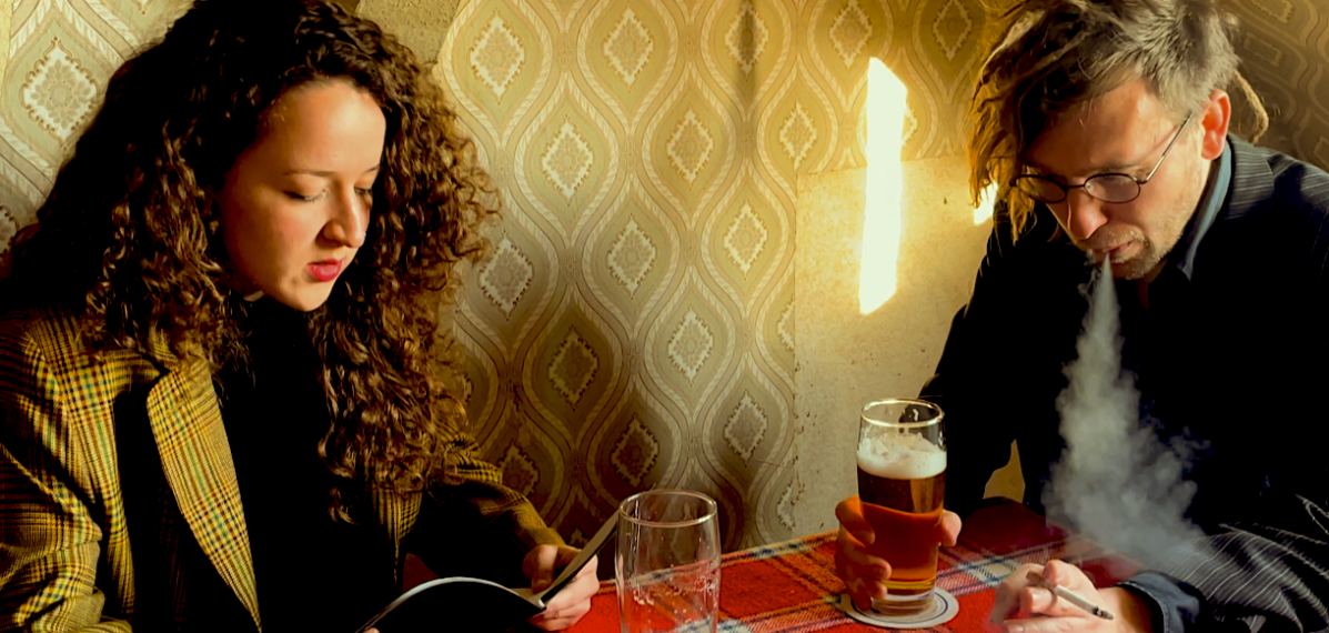 Das Foto zeigt die zwei Bandmitglieder von "Nun flog Dr. Bert Rabe", wie sie an einem Tisch sitzen, Bier trinken und rauchen.