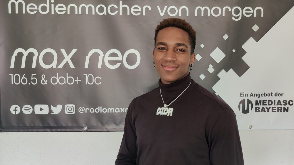 Das Foto zeigt den Rapper The Kid Dior im Porträt vor dem max neo Banner.