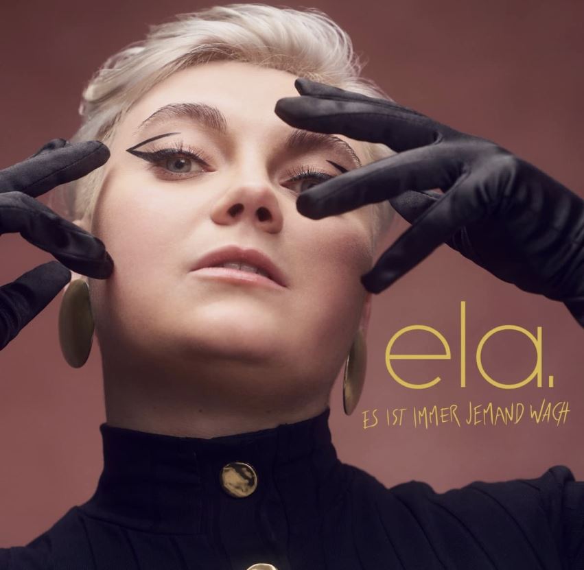 Das Albumcover "Es ist immer jemand wach" von Ela zeigt die Musikerin im Porträt. Sie schaut direkt in die Kamera.