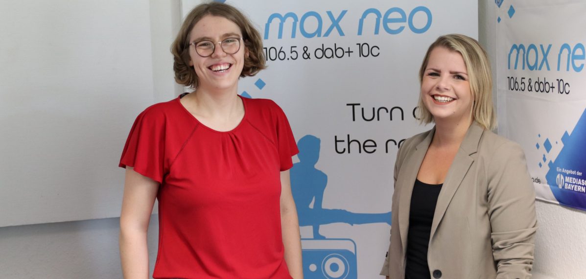 Das Foto zeigt Lena Schnelle und Julia Hacker vor einem max neo Aufsteller.