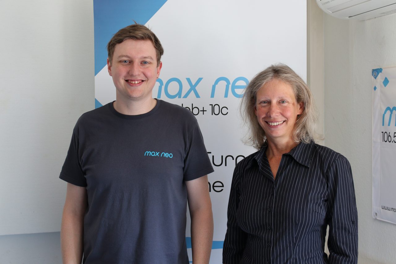 Das Foto zeigt Moritz Bayer und Sandra Güldenfuß vor einem max neo Aufsteller.