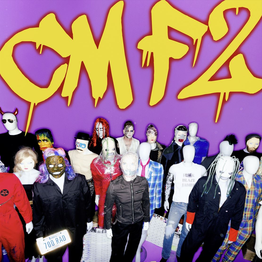 Das Albumcover "CMF2" von Corey Taylor ist lila. Auf dem Bild sind verschiedene Puppen zu sehen, die in einer Menge stehen. Darüber steht der Albumname in Graffiti.