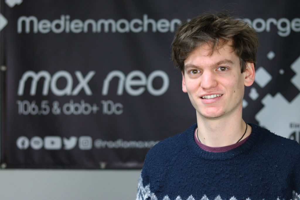 Das Foto zeigt Yannik Ambrusits im Porträt vor dem max neo Banner.