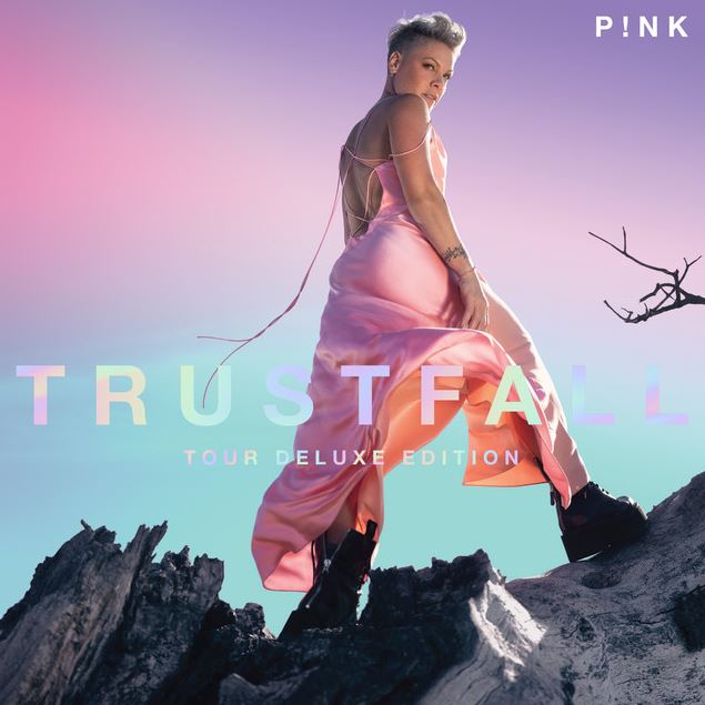 Das Albumcover "Trustfall (Tour Deluxe Edition)" von P!nk zeigt die Sängerin von hinten, wie sie auf einem Baumstamm steht und über die Schulter zur Kamera schaut.