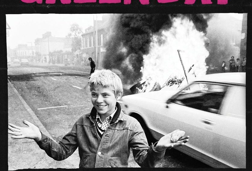 Das Albumcover "Saviors" von Green Day zeigt ein Schwarz-Weiß-Bild von einem Jungen, der auf einer Straße steht. Hinter ihm brennt etwas.