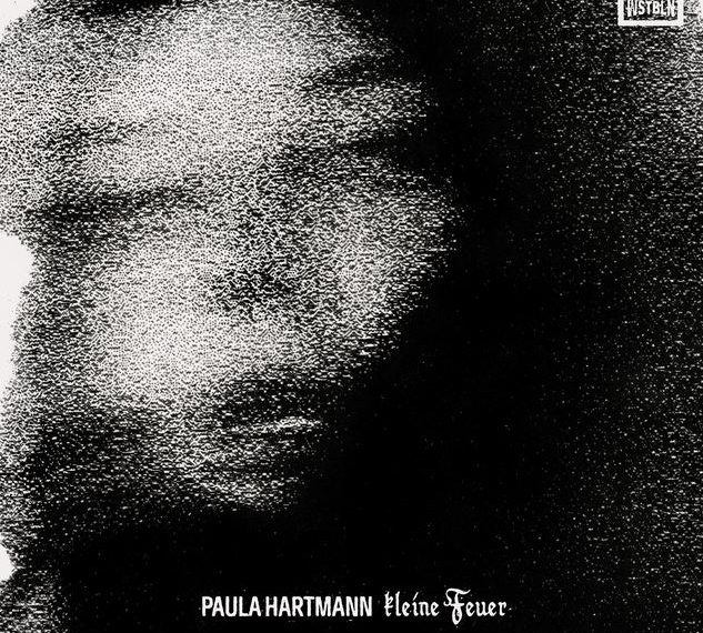 Das Albumcover "Kleine Feuer" von Paula Hartmann zeigt die Musikerin in einer verkörnten Schwez-Weiß-Aufnahme ihres Gesichts.