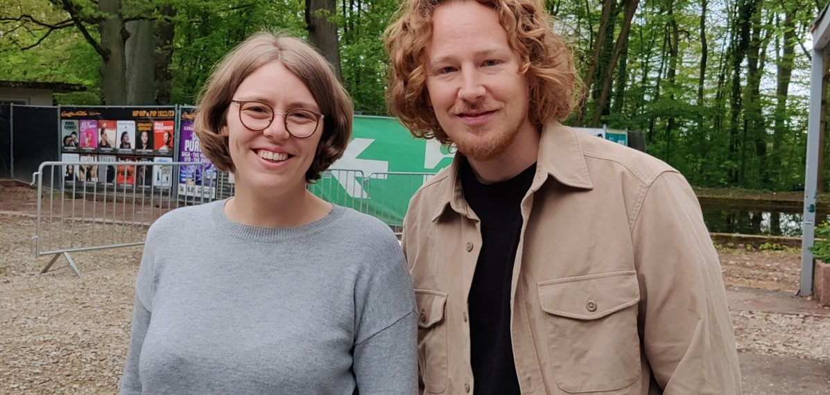 Das Foto zeigt den Musiker Michael Schulte mit max neo Moderatorin Lena Schnelle. Im Hintergrund sind Bäume zu sehen.