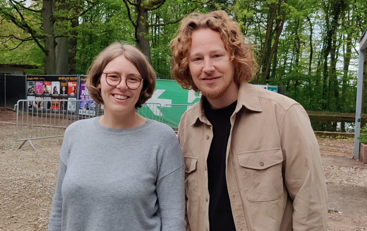 Das Foto zeigt den Musiker Michael Schulte mit max neo Moderatorin Lena Schnelle. Im Hintergrund sind Bäume zu sehen.