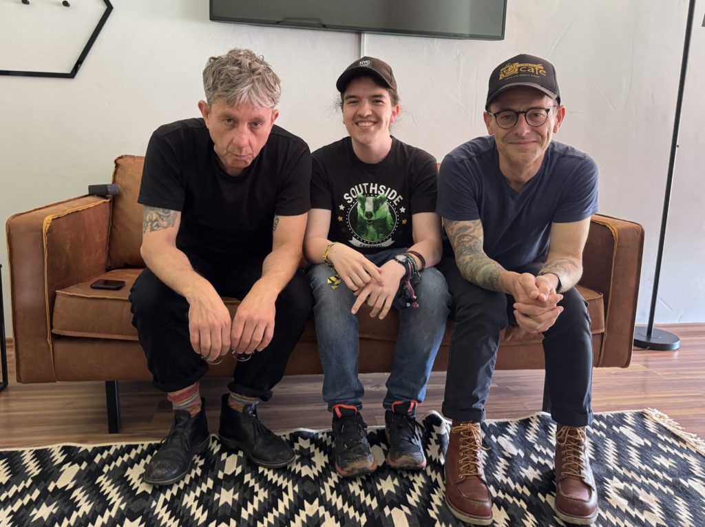 Das Foto zeigt Moderator Silas, der mit zwei Bandmitgliedern von den Beatsteaks auf einem Sofa sitzt.