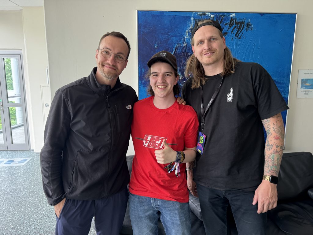 Das Foto zeigt Moderator Silas gemeinsam mit zwei Bandmitgliedern von Feine Sahne Fischfilet.