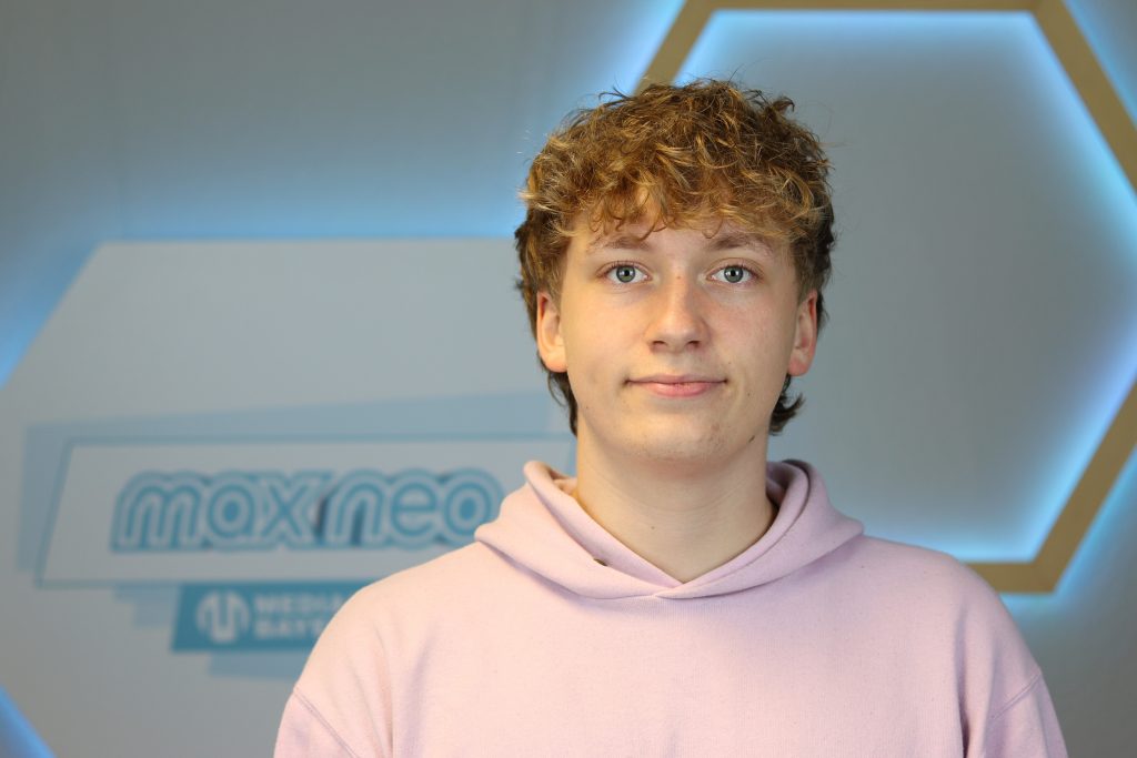 Das Foto zeigt Sebastian Weichelt im Porträt vor dem max neo Banner.