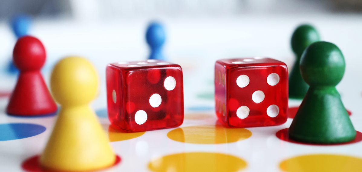 Das Foto ist ein Symbolbild zum Thema Spiele. Es sind Spielfiguren und Würfel zu sehen.
